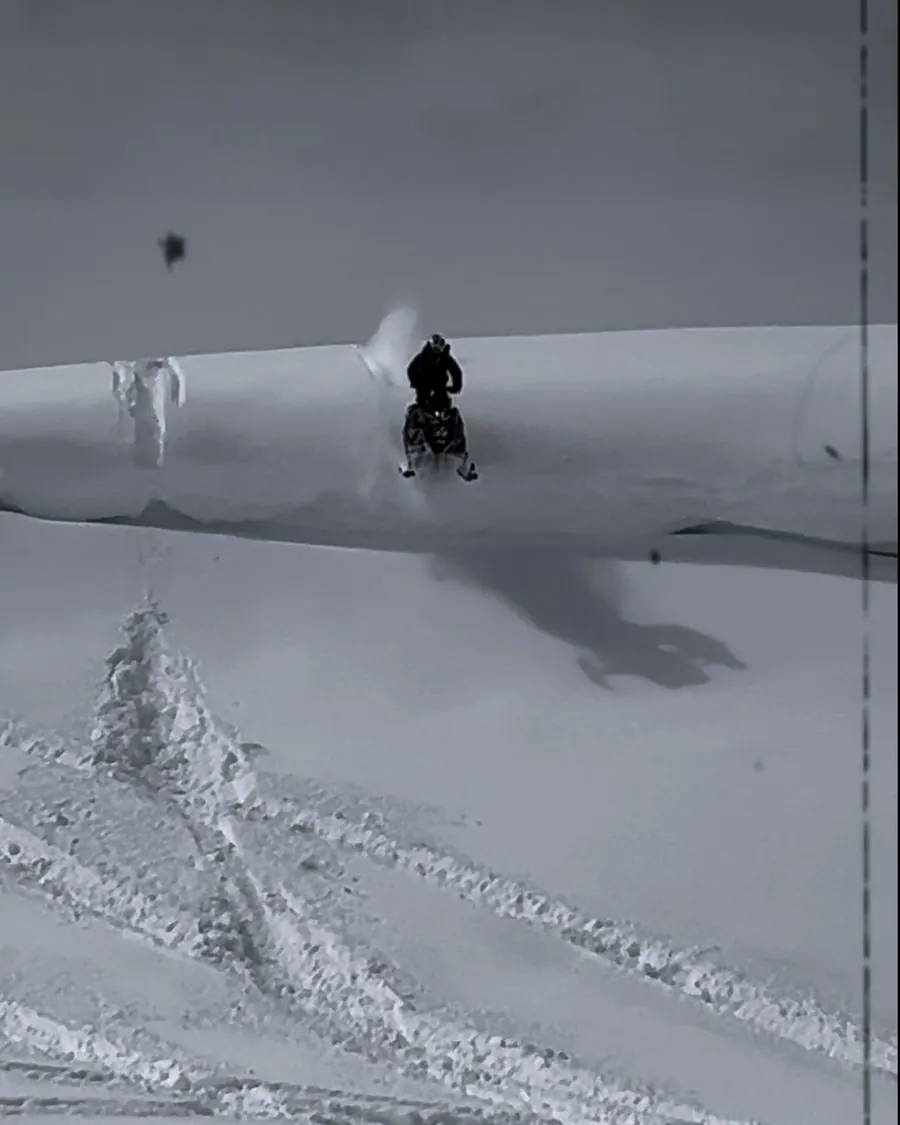 Snowmobile rider crossing an open mountain bowl