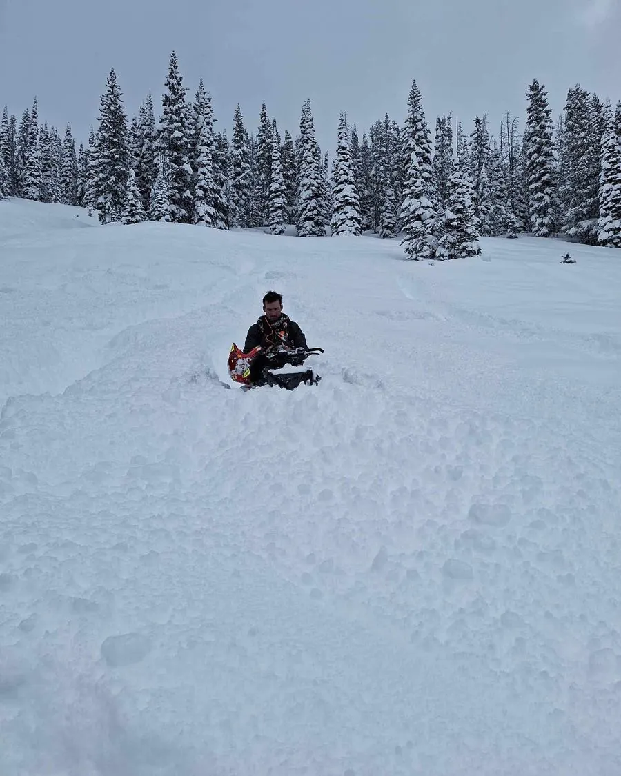 Snowmobilers stopped in an open snow bowl